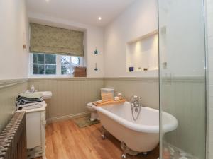 a bathroom with a bath tub and a toilet at Waterloo Mill Cottage in Wotton under Edge