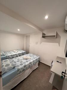 2 bedden in een kleine kamer met een bureau bij Manaira Suite 03 com 2 camas de solteiro ou 1 de casal in João Pessoa +7 foto's