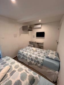 twee bedden in een kleine kamer met een tv bij Manaira Suite 03 com 2 camas de solteiro ou 1 de casal in João Pessoa