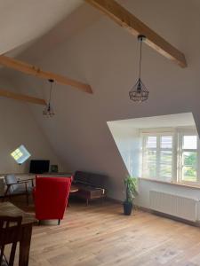 an attic room with a red chair and a table at In der Wassermühle in Melle +18 photos