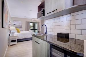 a kitchen with a sink and a bedroom with a bed at Ahoy Boutique Hotel in Gqeberha