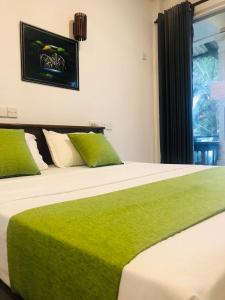 a bedroom with two beds with green sheets and a window at Coastal Heaven in Bentota