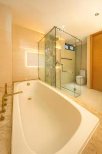 een groot wit bad in een badkamer met een douche bij The Seaview Kata in Kata Beach