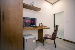 ein Zimmer mit einem Schreibtisch mit Fernseher und einem Stuhl in der Unterkunft De Thaphae Chiangmai in Chiang Mai