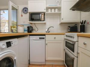 a kitchen with white cabinets and a washer and dryer at Tater-Du in Porthcurno +14 photos