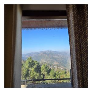 a window with a view of a mountain at The Sunrise Retreat in Solan