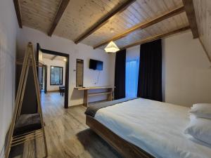 a bedroom with a large bed and a desk at Gray River Resort in Obarsia-Lotrului