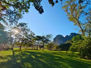 a park with trees and grass and mountains in the background at Sivilay Guesthouse in Vang Vieng