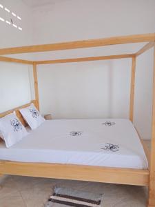 een bed met witte lakens en kussens erop bij Residence wa maore in Mahajanga
