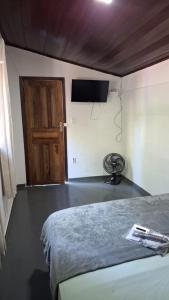 una camera con letto, televisore e porta di Pousada Três Irmãos a Parati