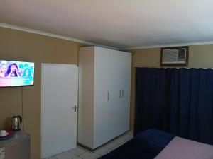 a bedroom with a bed and a tv on the wall at The Glen House in Durban
