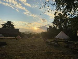 a group of tents in a field with the sunset at Amazing Mountain Camping, Bar&Grill in Ban Pang Hai