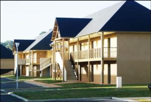 ein großes Gebäude mit einem blauen Dach und einer Treppe in der Unterkunft Studio moderne avec Balcon à 5 min de Honfleur parking et piscine in Équemauville