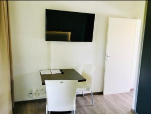 ein Zimmer mit einem Tisch, zwei Stühlen und einem Fernseher in der Unterkunft Studio moderne avec Balcon à 5 min de Honfleur parking et piscine in Équemauville