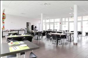 ein Esszimmer mit Tischen, Stühlen und Fenstern in der Unterkunft Studio moderne avec Balcon à 5 min de Honfleur parking et piscine in Équemauville