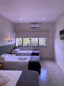 a bedroom with three beds and a large window at Pousada Primavera in Parnaíba