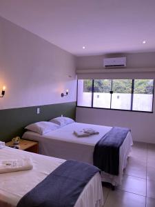 巴纳伊巴Pousada Primavera的一间有两张床和一扇窗户的酒店房间