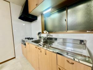 a kitchen with a stainless steel sink and wooden cabinets at VillaMonica Riverside in Nagoya