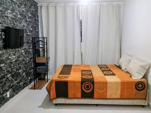 a bedroom with a bed and a television in it at Flat confortavel e aconchegante in Cabo Frio