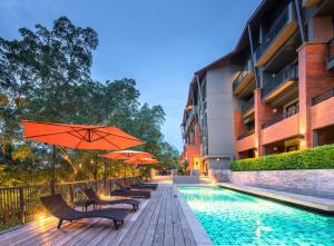 una piscina con sillas y sombrillas junto a un edificio en Rimnaam Klangchan Hotel - SHA Plus, en Chanthaburi