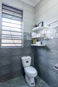 a bathroom with a white toilet and a window at Mivida Residences in Bulindo