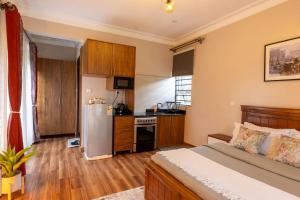 a bedroom with a bed and a kitchen with a refrigerator at Mivida Residences in Bulindo
