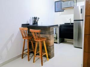 a kitchen with two wooden stools at a counter at Flat confortavel e aconchegante in Cabo Frio