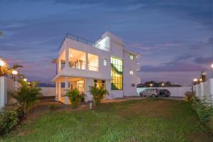 een groot wit huis met een auto in een tuin bij ll EMPYREAN STAY ll BIG DADDY VILLA ll 6BHK ll AC ll PRIVATE POOL ll BACHELORS FRIENDLY ll in Malavli