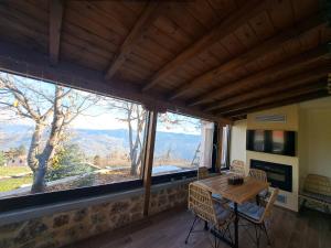 una sala da pranzo con un tavolo e una grande finestra di Αυγήλιον - Private Mountain House a Synikia Mesi Trikalon