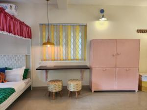 a bedroom with a bed and a pink cabinet and stool at Florin Studio in Vagator