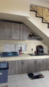 a kitchen with gray cabinets and a sink and a staircase at Puncak azoul villa in Cinengangirang
