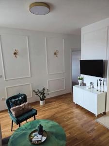 een woonkamer met een tv, een stoel en een tafel bij Apartman N Pale in Pale