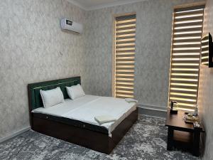 une chambre avec un lit, une table et des fenêtres dans l'établissement Rubin Hotel, à Navoï