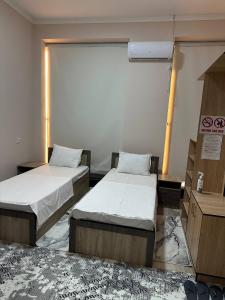 une chambre avec deux lits et une fenêtre dans l'établissement Rubin Hotel, à Navoï 3 autres photos