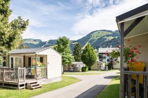 a small house with a porch and mountains in the background at Camping L'Oustalet in Châtel