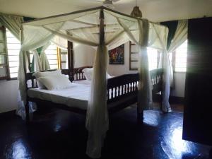 a bedroom with a canopy bed with white pillows at Casa Bella 4 Bedroom Villa in Watamu
