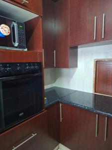 une cuisine avec des armoires en bois et un micro-ondes noir dans l'établissement Number 8, à Maseru