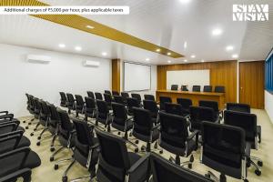 une salle de conférence avec des chaises noires et un podium dans l'établissement StayVista at Thalassa Near The Beach, à Alibaug