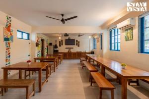 une salle à manger avec des tables et des bancs en bois dans l'établissement StayVista at Thalassa Near The Beach, à Alibaug