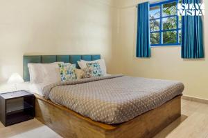 une chambre avec un lit, des rideaux bleus et une fenêtre dans l'établissement StayVista at Thalassa Near The Beach, à Alibaug