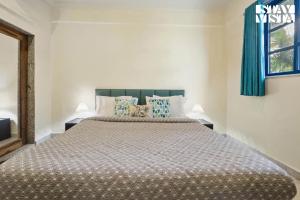 une chambre avec un grand lit avec des rideaux bleus dans l'établissement StayVista at Thalassa Near The Beach, à Alibaug 3 autres photos