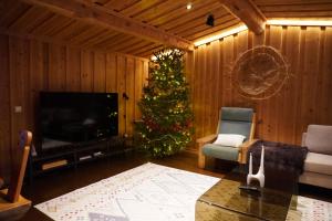 a living room with a christmas tree and a television at Villa Tolonen a beautiful log villa by the Ivalo River in Ivalo +89 photos