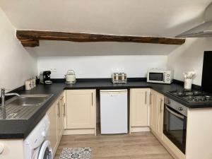 a kitchen with a white refrigerator and a sink at tillys Cottage in Folles