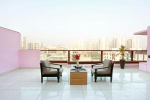 een kamer met twee stoelen en een tafel en een balkon bij Hotel Emerald Suites & Banquet By Aura in Noida