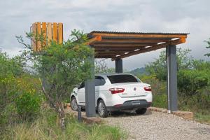 ein weißes Auto, das unter einer Holzkonstruktion parkt in der Unterkunft Tintitacos in Los Hornillos