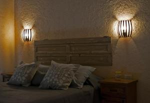 ein Schlafzimmer mit einem Bett mit zwei Lichtern an der Wand in der Unterkunft Tintitacos in Los Hornillos