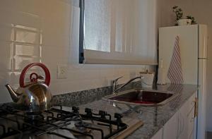 een keuken met een wastafel en een fornuis met een waterkoker bij Tintitacos in Los Hornillos +3 foto's