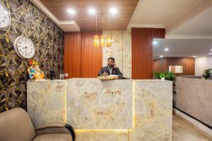 Een man met een mobieltje in een lobby. bij Hotel Emerald Suites & Banquet By Aura in Noida