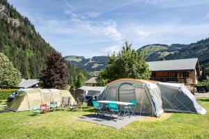 a group of tents in a field with a table and chairs at Camping L'Oustalet in Châtel +21 photos
