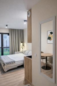 a bedroom with a bed and a table and a mirror at Apartments Rajska 77 in Wrocław